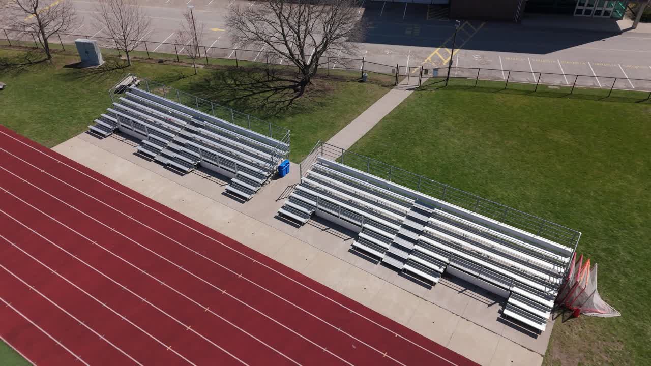 Stigende droneoptagelse af tomme tribuner med løbebane i forgrunden.
