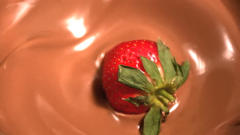 strawberry dropping into melted chocolate close up