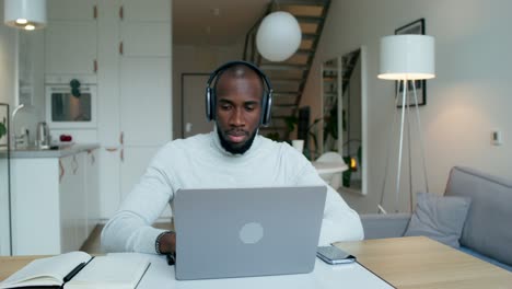 man working from home on laptop with headphones