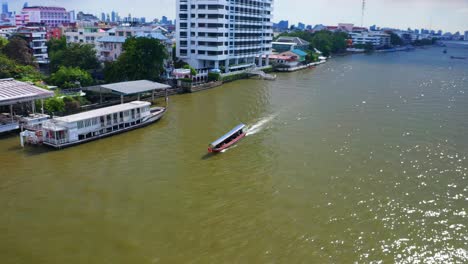 traditional tourist boat sailing across chao phraya river in bangkok city, thailand