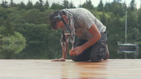 sanding boat wheelhouse roof planks with sandpaper wearing mask