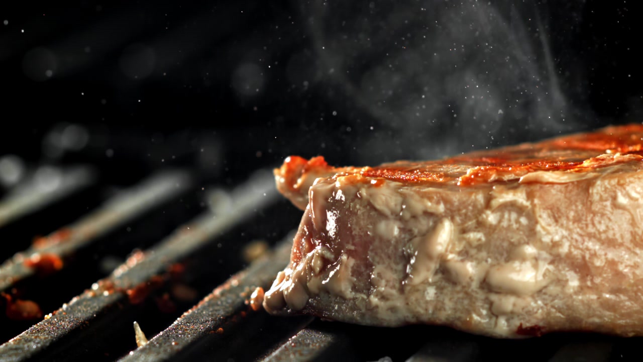 Close-up of a Steak Grilling on a Hot Barbecue with Smoke
