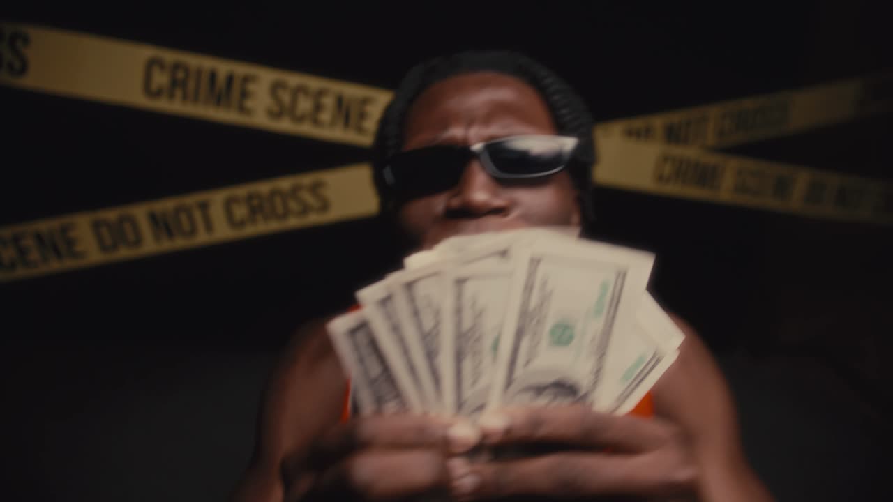 Black Man Holding Cash and Rapping to Camera at Crime Scene with Police Lights