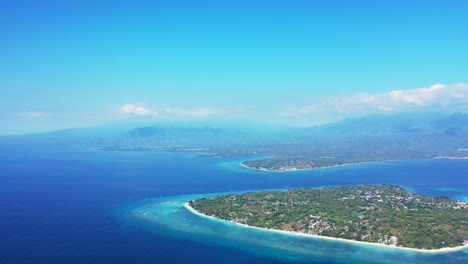 blue seascape at fogy morning, light blue sky with white clouds over low-lying tropical islands surrounded by calm blue sea in indonesia