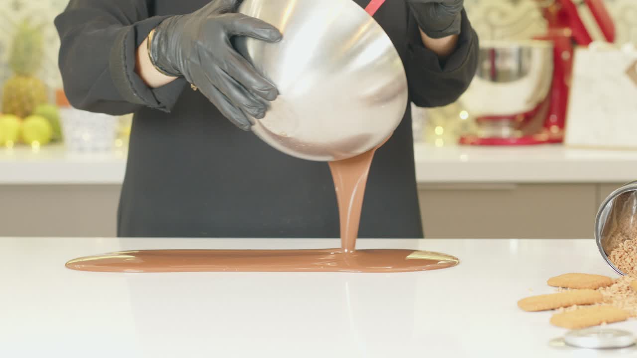 cioccolato fuso che versa sul tavolo dallo chef in grembiule nero
