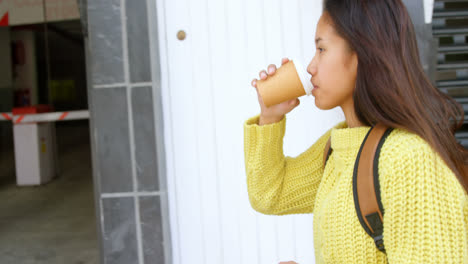 Teenage-girl-drinking-coffee-while-walking-on-sidewalk-4k