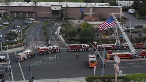 firefighters, fire trucks, and police officers wait for a funeral procession, to show their support for a fallen officer