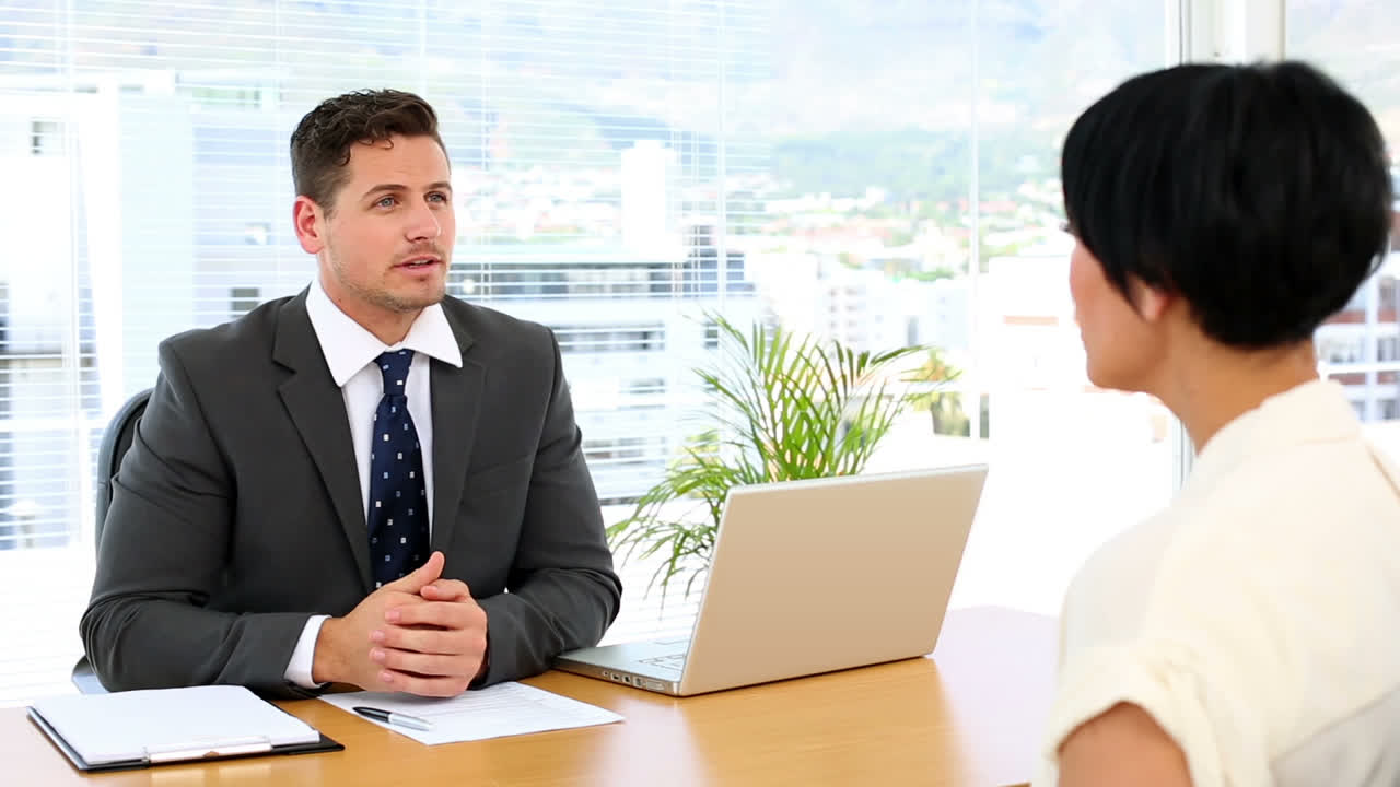 Handsome businessman with laptop interviewing a businesswoman