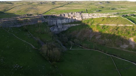 el sol se pone sobre el acantilado rocoso mientras la sombra se mueve sobre las rocas en el campo inglés desde el avión no tripulado en malham tarn y gordale scar gorge