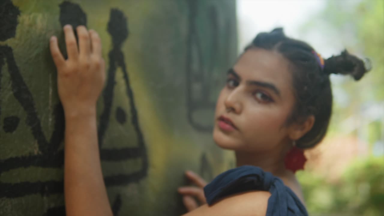 Sensual woman's face in nature environment with hands on the wall with historical drawings