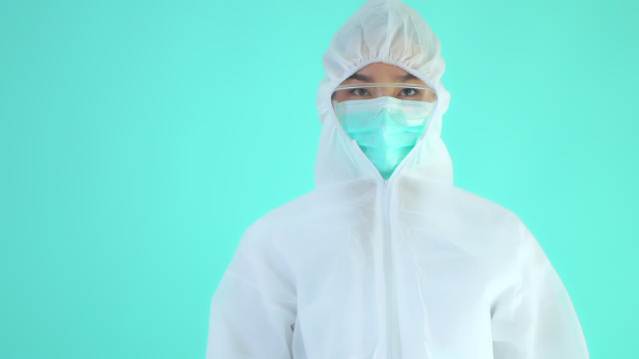 Profile of Medical Person in Protective Virus Clothing Showing Pills. Isolated on Turquoise Background