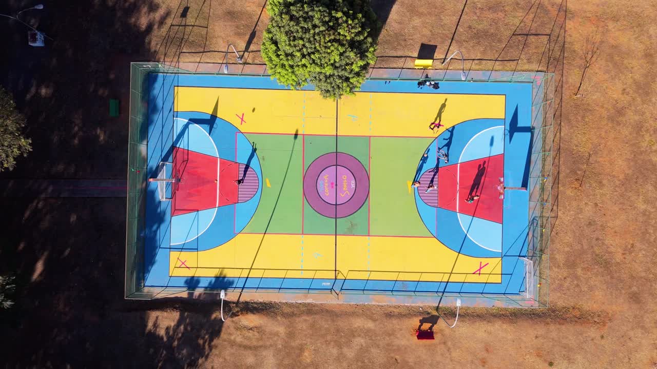 jóvenes jugando al baloncesto en una cancha colorida en brasil