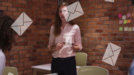 Animation-of-envelopes-moving-over-diverse-businesswoman-with-tablet-explaining-to-colleagues