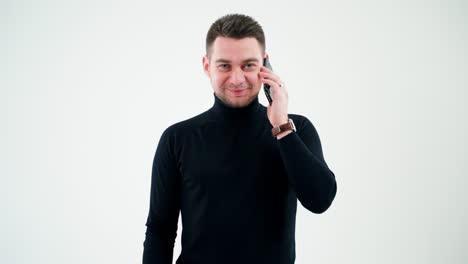 portrait of a smiling man talking on the phone. handsome businessman in black sweater talking on a mobile phone isolated in white studio.