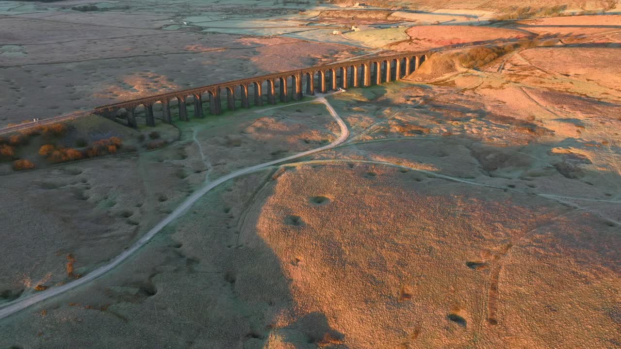 길고 아치가 있는 철도 다리 는 황폐 한 겨울 의 습지 에서 이른 아침 빛 을 받으며  도로 를 가지고 있다