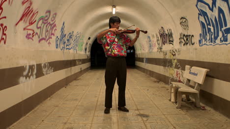 escena cautivadora de un músico tocando melodías melódicas en el violín en un túnel de graffiti