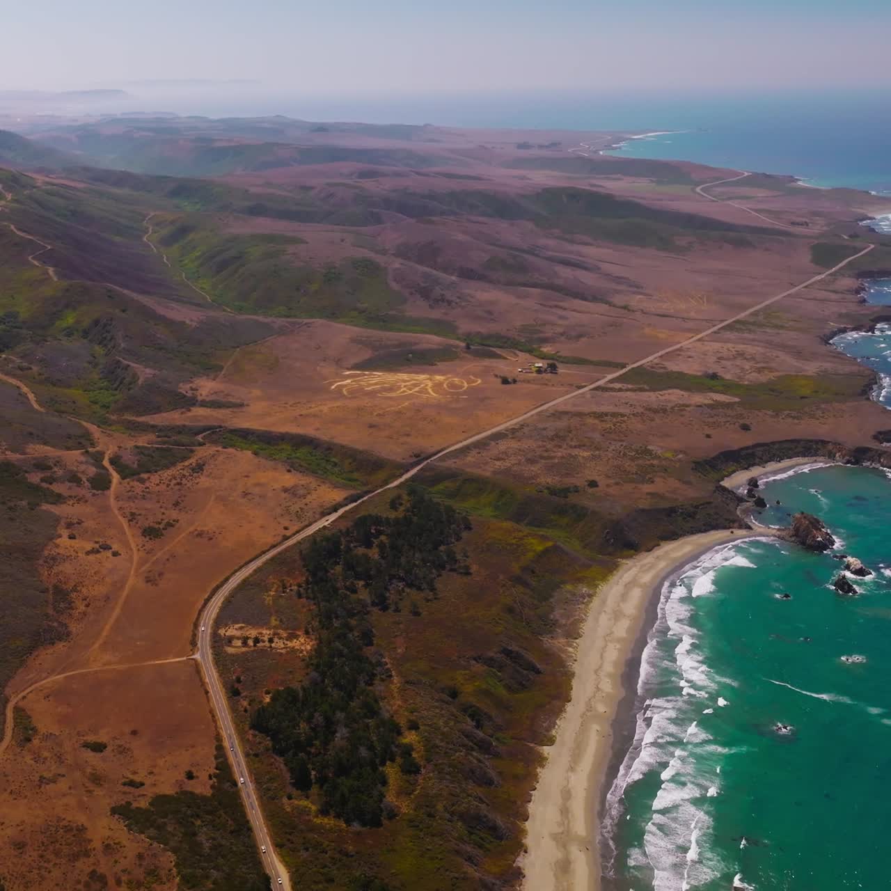 Flight over the mountainous shore of the Pacific ocean in California, USA. Highway going along the rocky landscape along the water