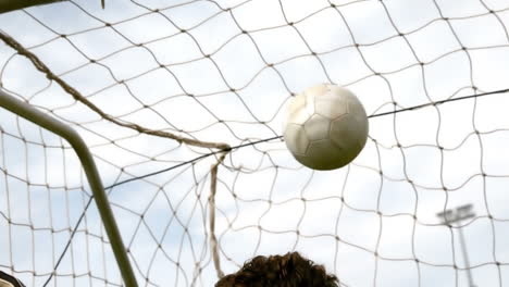 goalkeeper in red letting in a goal during a game