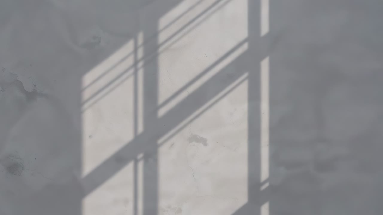 Shifting sunlight nudging paned window shadow across painted plaster wall in room with 3 thin lines