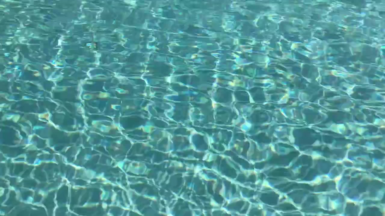 Air kolam renang biru muda toska bergerak di bawah sinar matahari di Bali, Indonesia