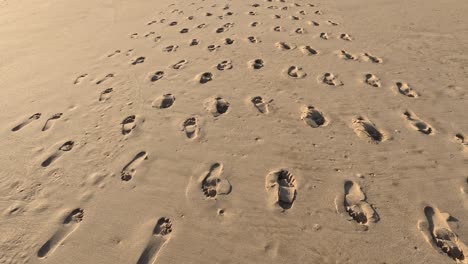 The-camera-moves-after-the-tracks-and-footprint-of-the-humans-left-on-sandy-beach-,-in-Morocco