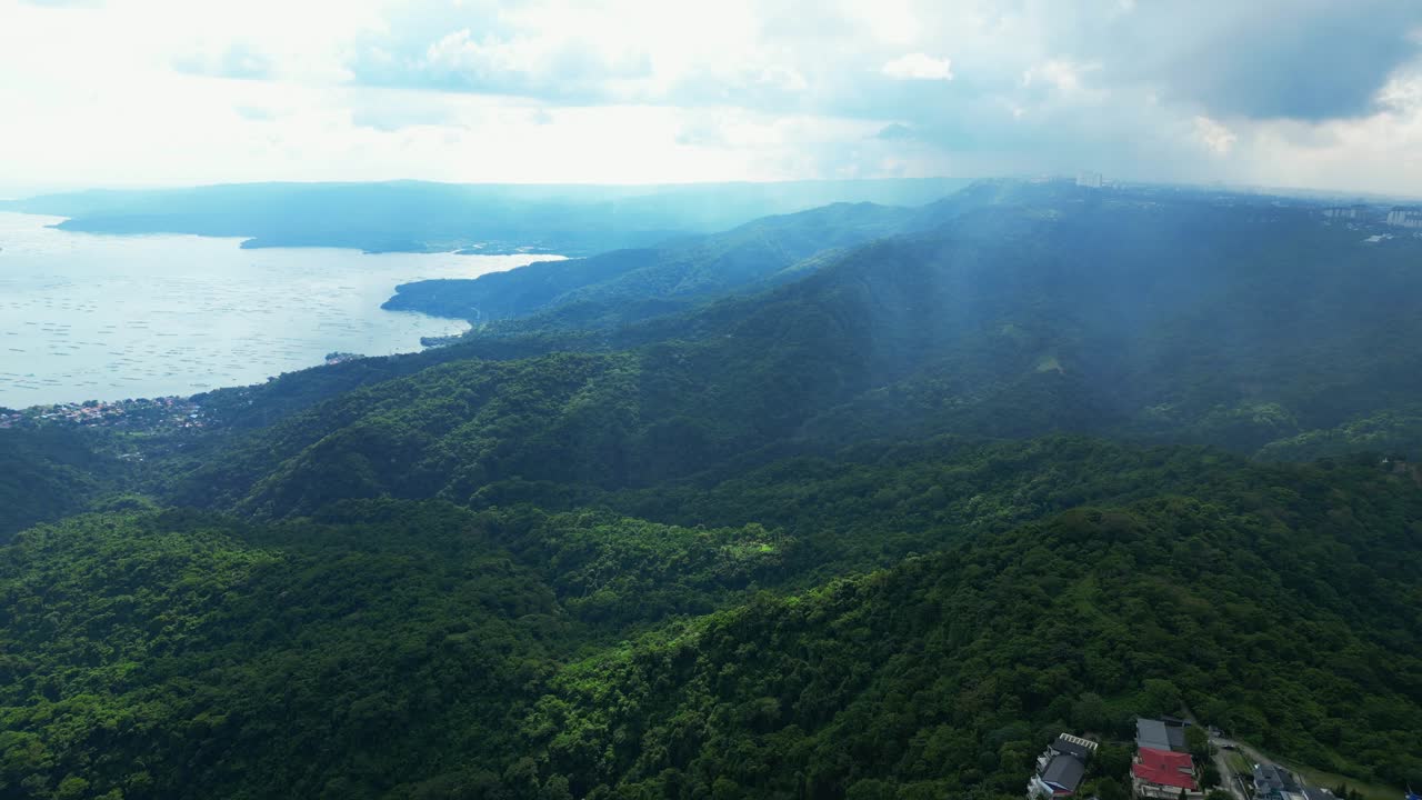 A misty aerial of forested hills with Taal Lake stretching along the left edge in Tagaytay, Cavite, Philippines