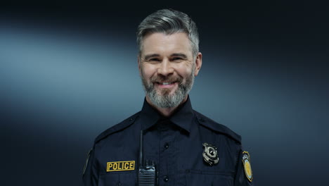 portrait shot of the young good looking and joyful policeman with gray hair smiling to the camera