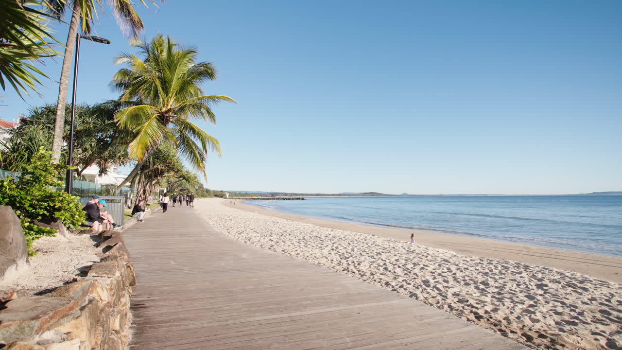 noosa encabeza la playa principal paseo marítimo junto a la playa tropical con palmeras, cámara lenta de 4k