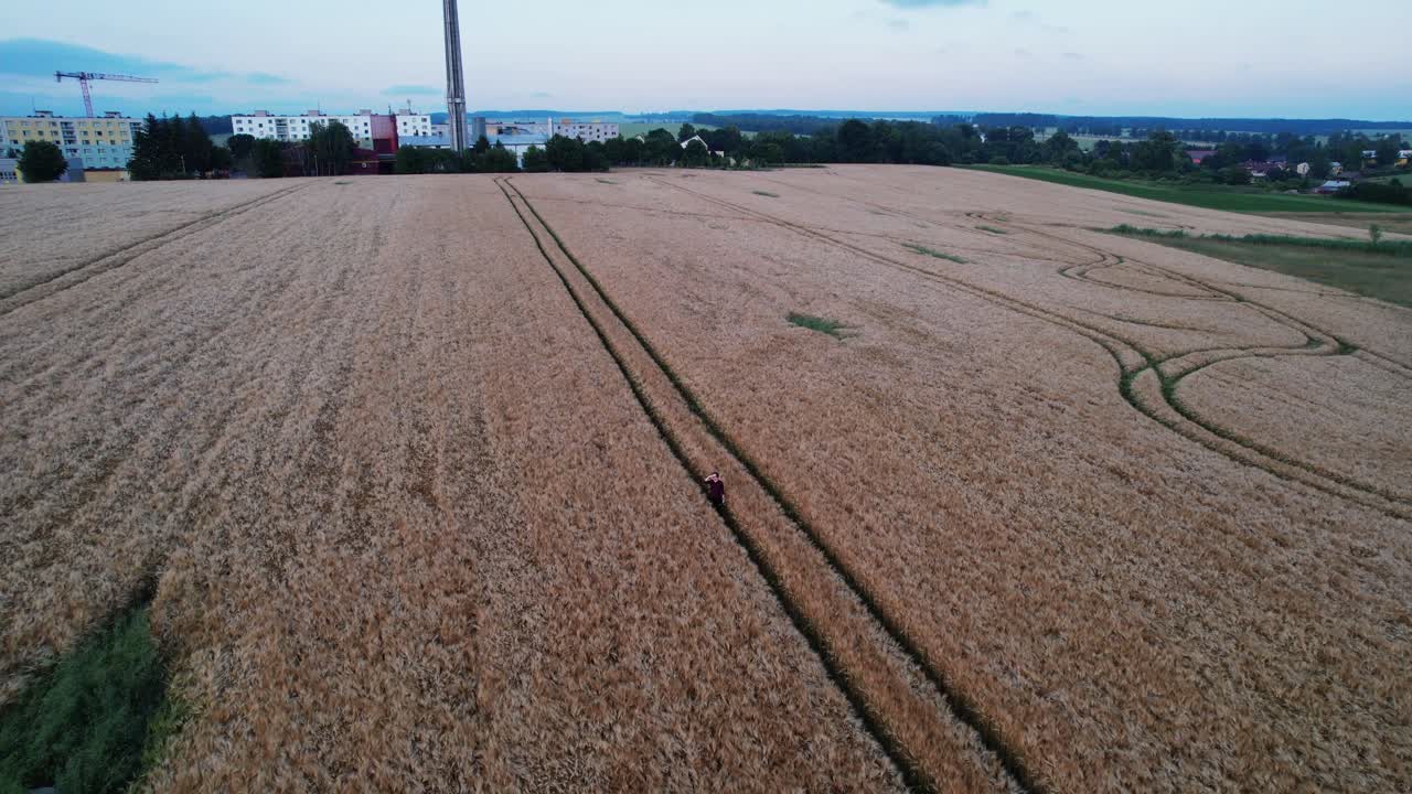 Distant view of a man in a field outside the city in the summer evening