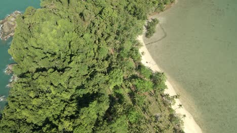 Aerial-ascending-shot-looking-down-on-tropical-island-beach,-jungle-and-rocky-coastline