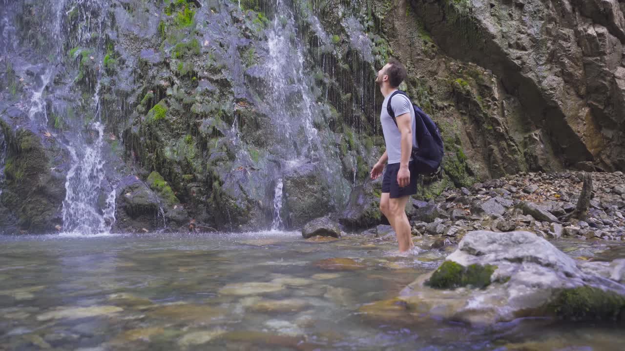 맨발로  ⁇ 고 있는 남자가 폭포를 바라보고 있다.