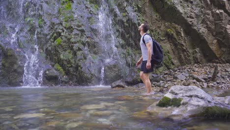 hombre caminando descalzo mira la cascada.