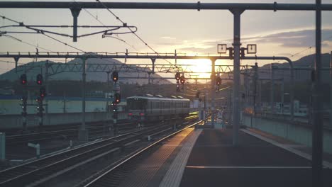 a japanese train slowly heading towards the sunset direction in kyoto, japan - wide shot