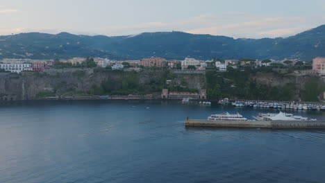 Aerial-footage-moving-to-the-left-showing-off-more-and-more-of-the-cliffs-and-coast-of-the-town-of-Sorrento,-Italy