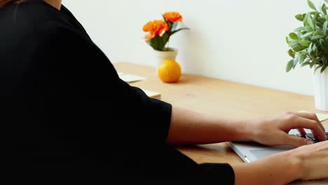 ejecutiva sentada en un escritorio y usando una computadora portátil