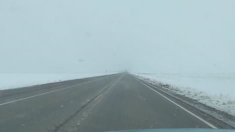 Winterfahrt-Auf-Einer-Langen-Straße-Mit-Wenig-Verkehr,-In-Einer-Eisigen-Landschaft,-Bei-Nebel-Und-Schneefall