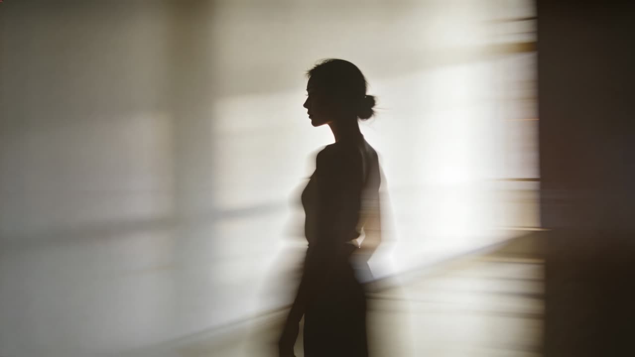 Donna in movimento che si sposta in studio, retroilluminazione della griglia della finestra che crea un effetto fantasma sfocato, in abito aderente