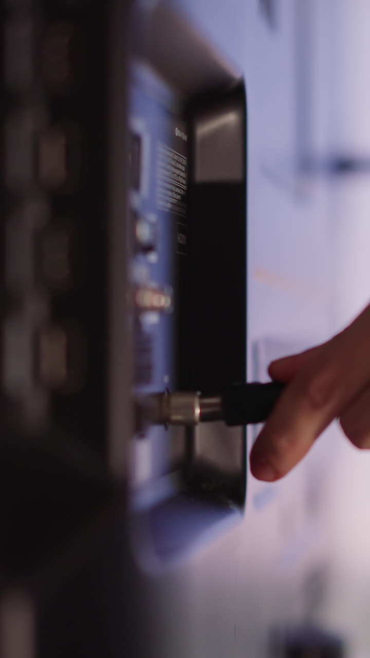 Man hand plugs cable to smart TV on blurred background in apartment closeup slow motion. Technician tunes contemporary device at home. Electrical equipment