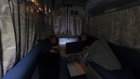 two women relaxing in their cozy converted van at night
