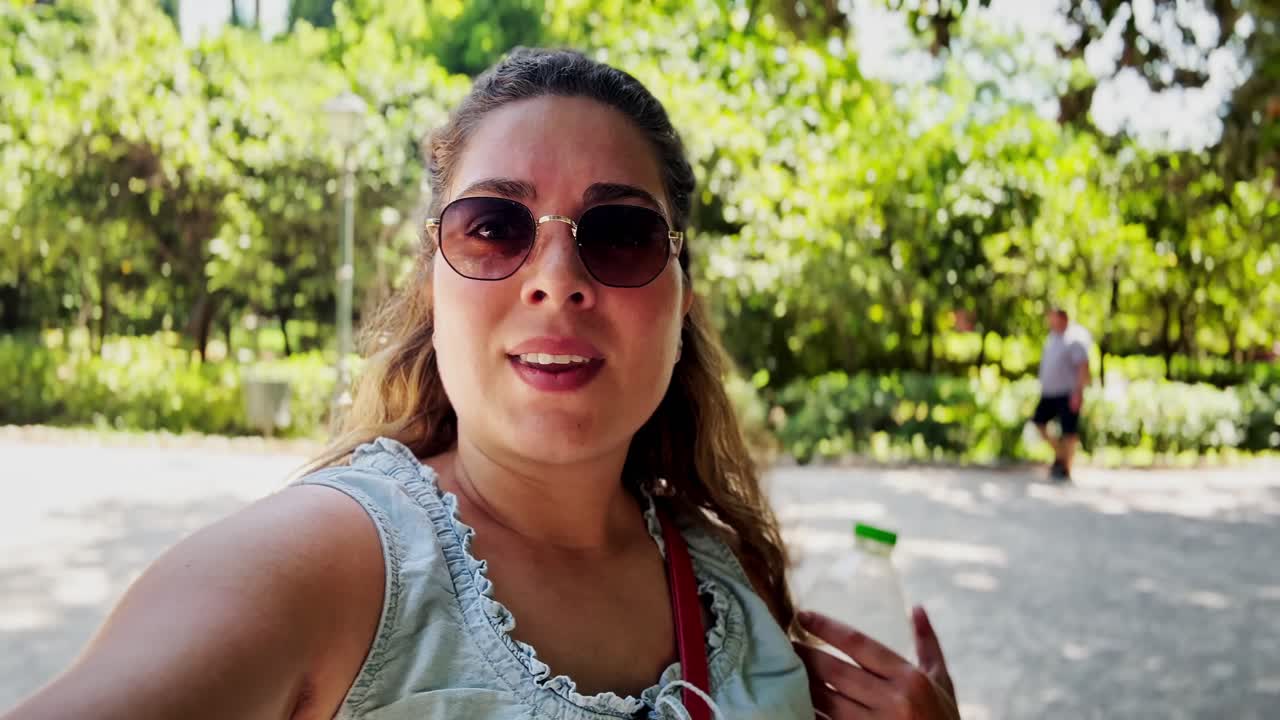 Giovane donna turista che fa vlogging delle sue avventure nel Giardino Nazionale di Atene.