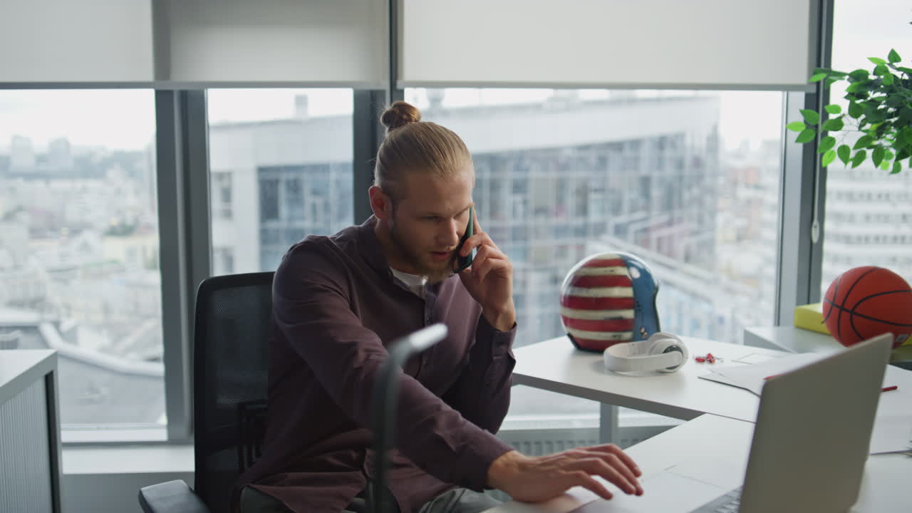 hombre de negocios sonriente conversación telefónica en la oficina de primer plano. hombre mirando la computadora portátil
