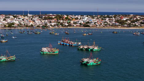 commercial fishing boats floating over the white sand peninsula of vietnam's historic fishing village