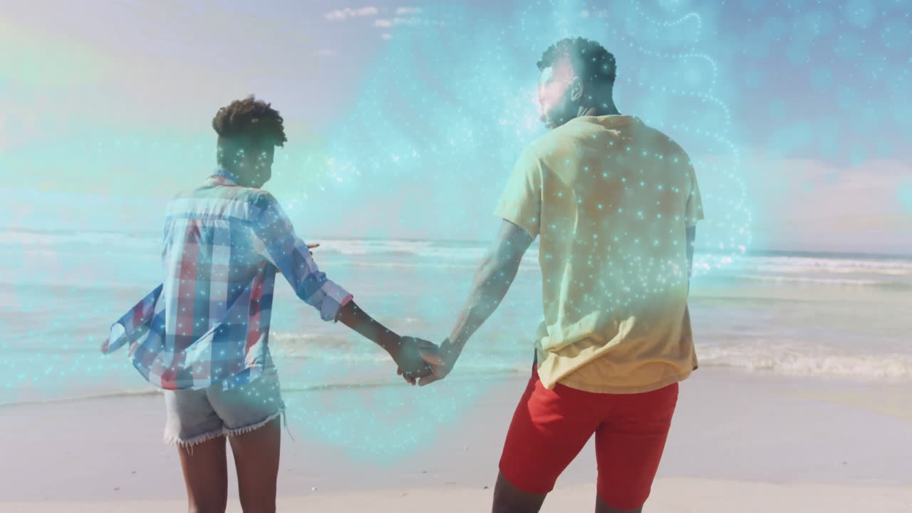 Couple holding hands on beach with sparkling blue animation overlay