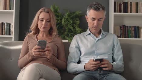 mature male and female using a smartphone. phone and work addiction.