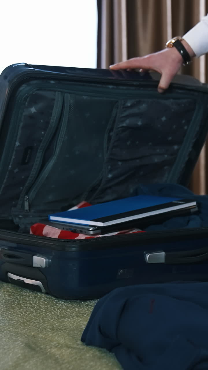 Businessman packing his clothes. Hands of businessman packing his suitcase in hotel room. Vertical video
