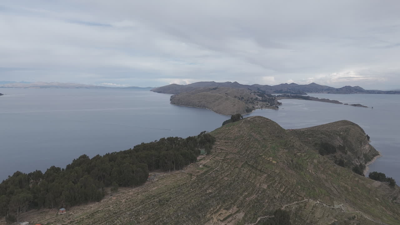 Drone shot above Isla Del Sol near Copacabana Bolivia Titicaca lake on a cloudy day with view on the sea and the islands LOG