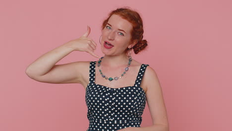 red hair young woman seller looking at camera doing phone gesture like says hey you call me back
