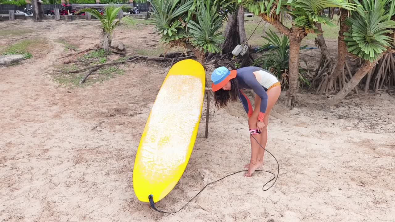 mujer preparándose para surfear en una playa tropical