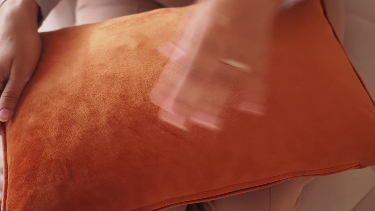 Close-up of hands touching a soft orange cushion