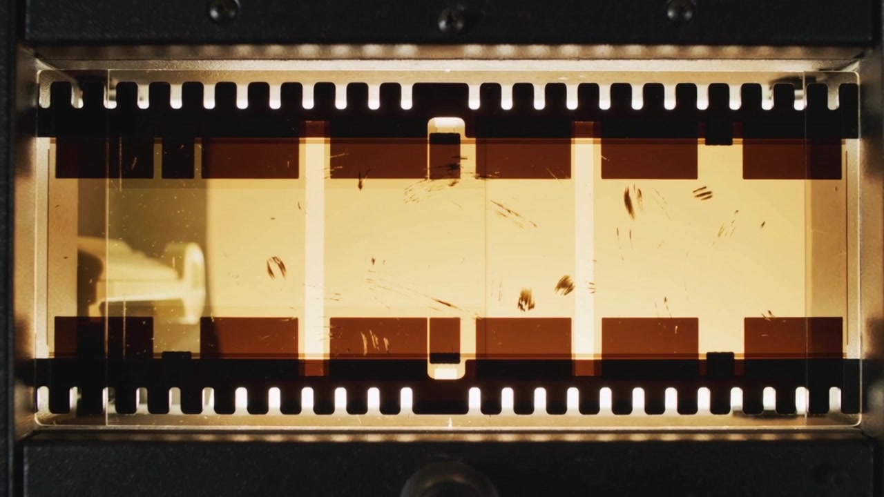 Vorlaufender 35mm Filmstreifen bewegt sich durch das Filmtor nach Zahnrad-Eingriff zur Projektion.